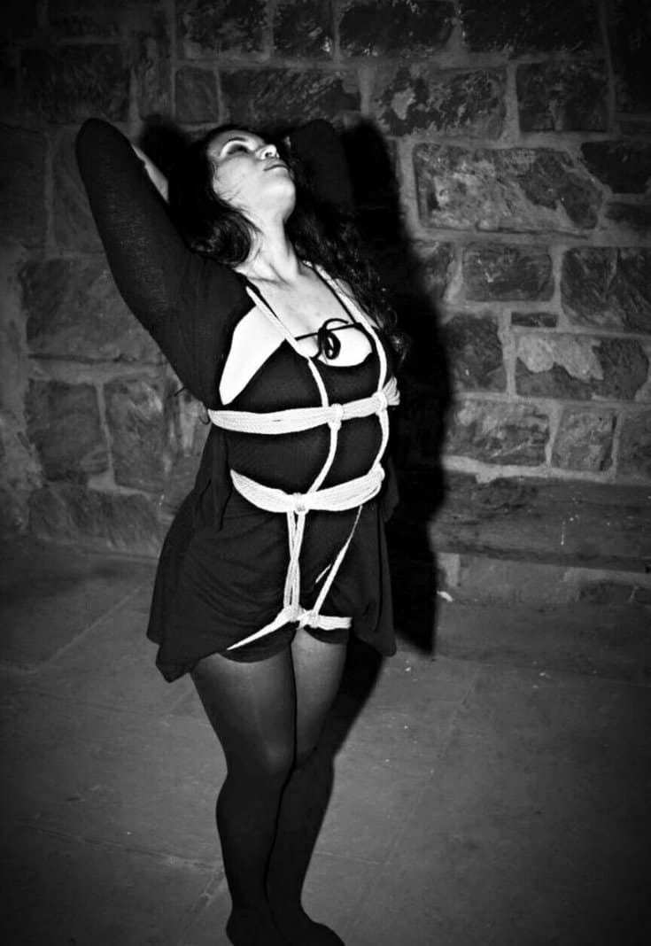Aeaea in a black-and-white rope study against a stone wall